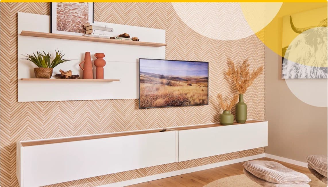 Wohnzimmer mit Wandregalen, Vasen, Pflanzen und Flachbild-TV. Chevron-Tapete und Sitzkissen auf dem Boden.