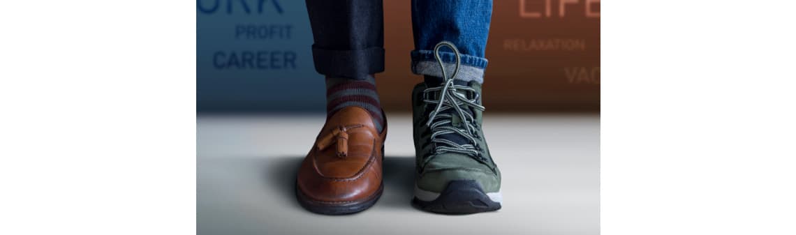 Eine Person trägt gleichzeitig einen braunen Lederslipper und einen grünen Wanderschuh.