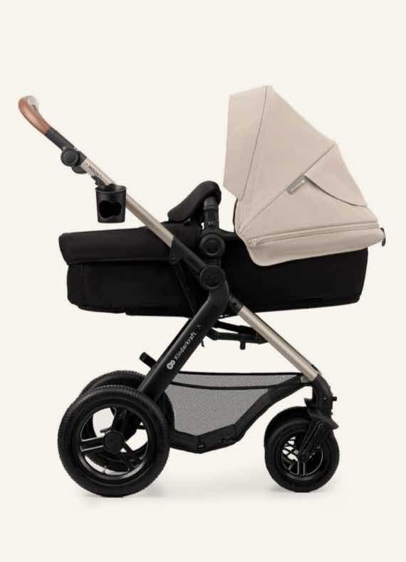 Kinderwagen mit schwarzem Rahmen und beiger Babywanne, Becherhalter am Griff befestigt