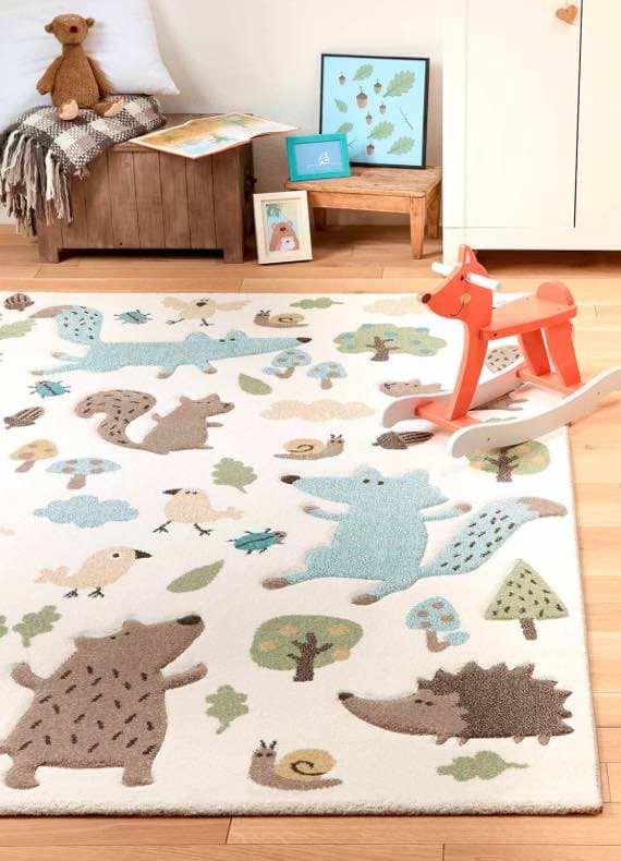 Kinderzimmer mit Teppich, der Waldtiere zeigt, und rotem Schaukelpferd. Im Hintergrund ein Holzhocker mit Deko und Kissen.
