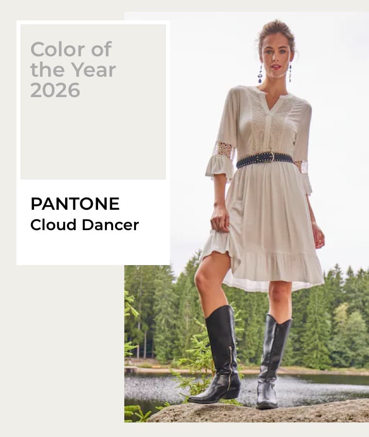 Color of the Year 2026 – PANTONE Cloud Dancer – Frau in weißem Kleid und schwarzen Stiefeln steht vor einem See und Wald