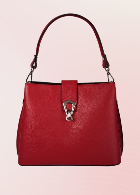 Rote Handtasche mit Metallverschluss und abnehmbarem Schulterriemen vor rosa Hintergrund