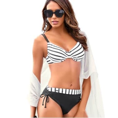 Frau trägt gestreiften Bikini mit schwarzem Unterteil und weißer Strandjacke.