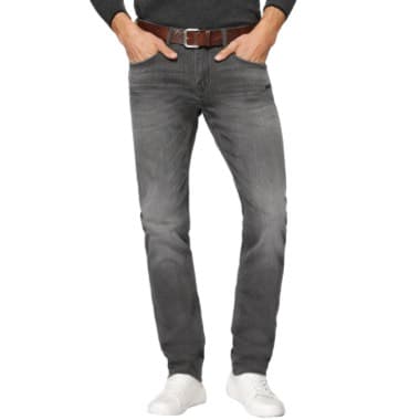 Person trägt graue Jeans, braunen Gürtel und weiße Sneakers, Hände in den Taschen