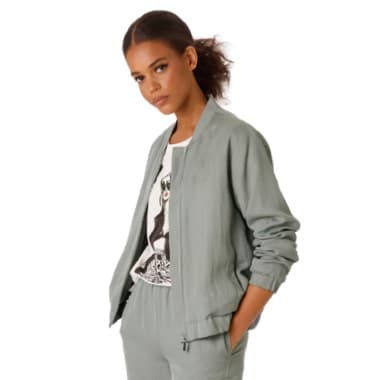 Frau trägt graue Jacke und Hose, darunter ein bedrucktes weißes T-Shirt