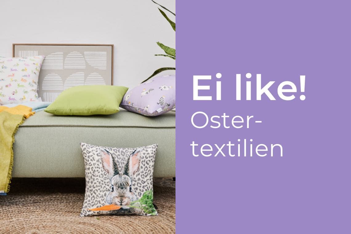 Ei like! Ostertextilien – Sofa mit bunten Kissen und Hasenkissen mit Karotte.