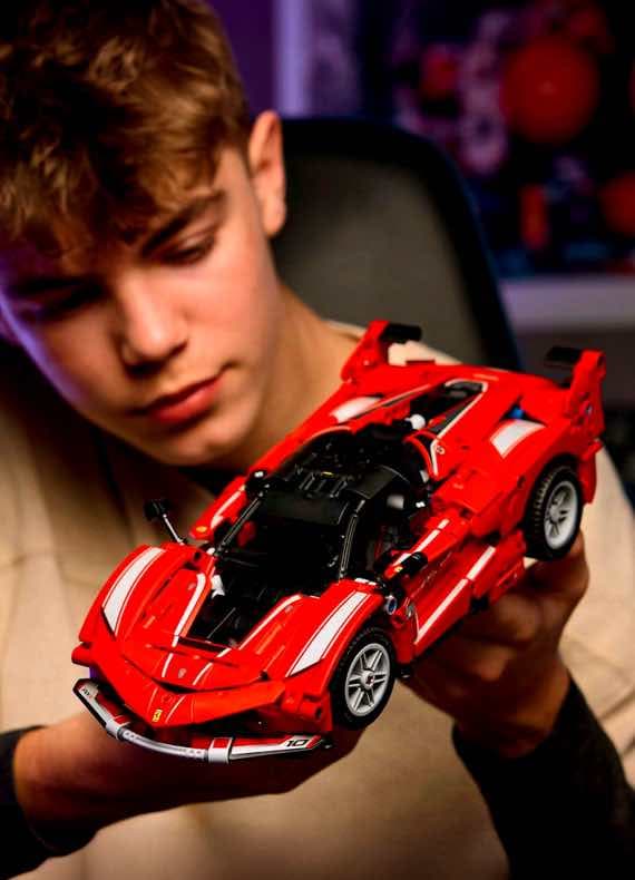 Person hält rotes Modellauto, das einem Rennwagen ähnelt, vor die Kamera.