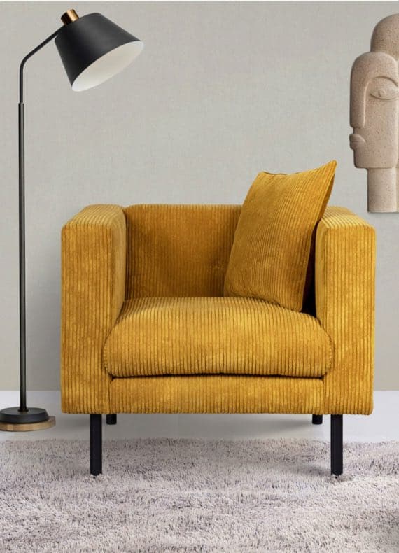 Gelber Sessel mit Kissen auf grauem Teppich neben einer schwarzen Stehlampe und einer abstrakten Wanddekoration