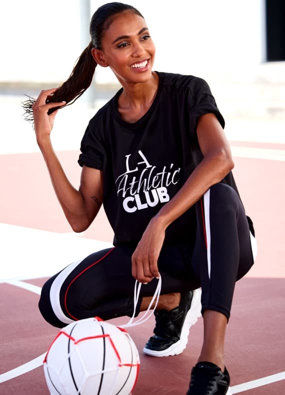 LA Athletic Club – Person im Sportoutfit kniet auf dem Spielfeld und hält Ball und Schuhsenkel