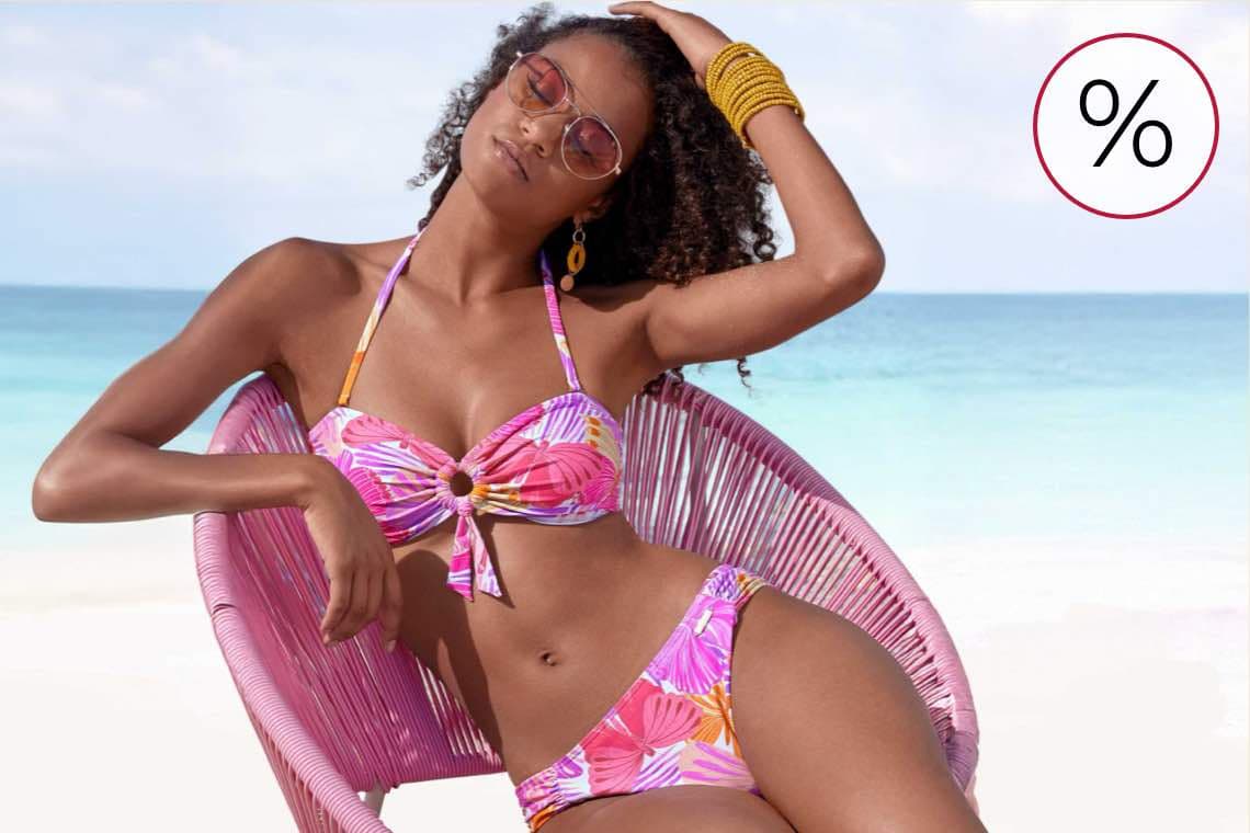 %-Zeichen für Rabatt – Frau im bunten Bikini lehnt entspannt im Stuhl vor Meer und hellem Sandstrand
