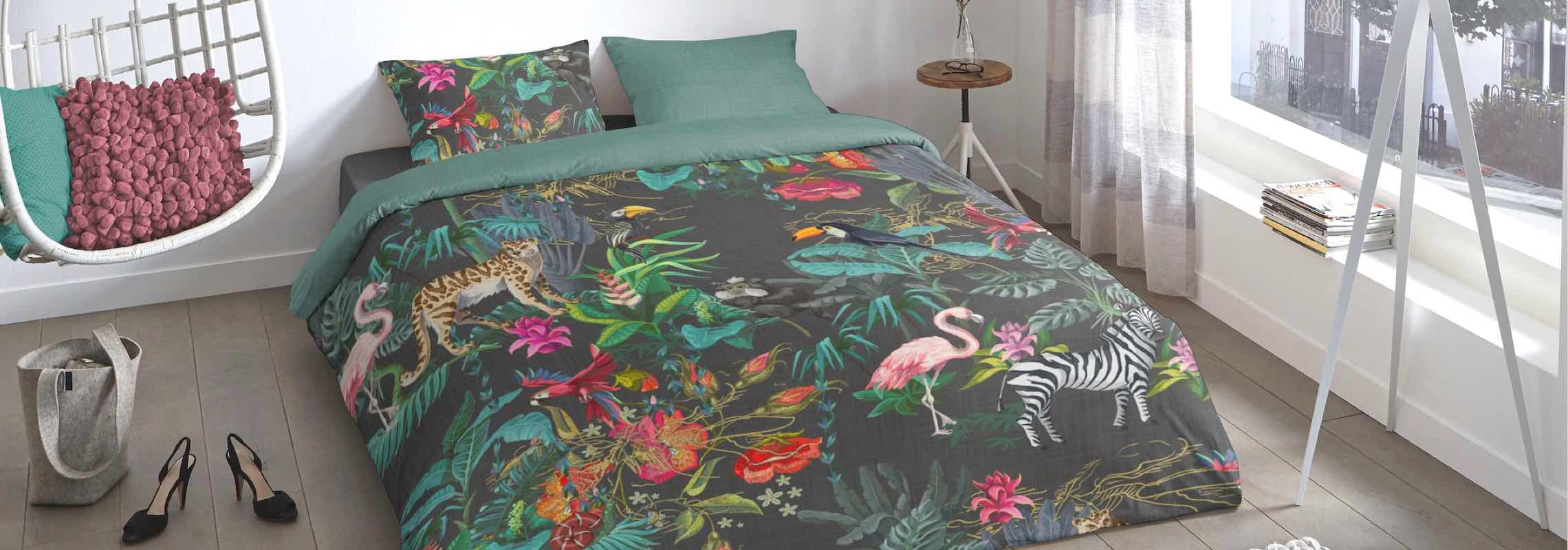 Bett mit dunkelgrauer Bettwäsche, bunt bedruckt mit Dschungelpflanzen, Leopard, Flamingo, Zebra und Vögeln