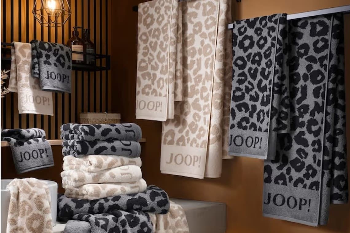 JOOP! Handtücher mit Leo-Muster in Beige und Grau, gefaltet und hängend im Badezimmer auf Regal und Stange