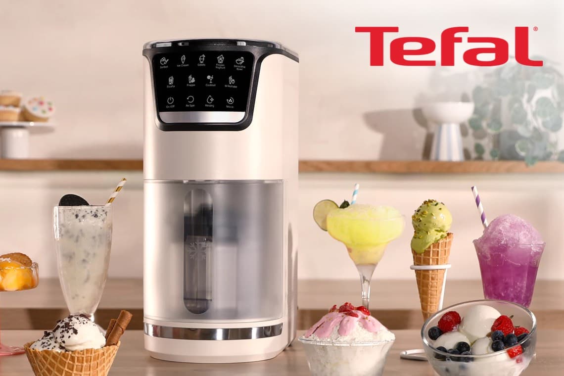 Tefal Eismaschine auf Küchentisch, umgeben von Eisbechern, Waffel mit Kugel, Sorbets und bunten Getränken