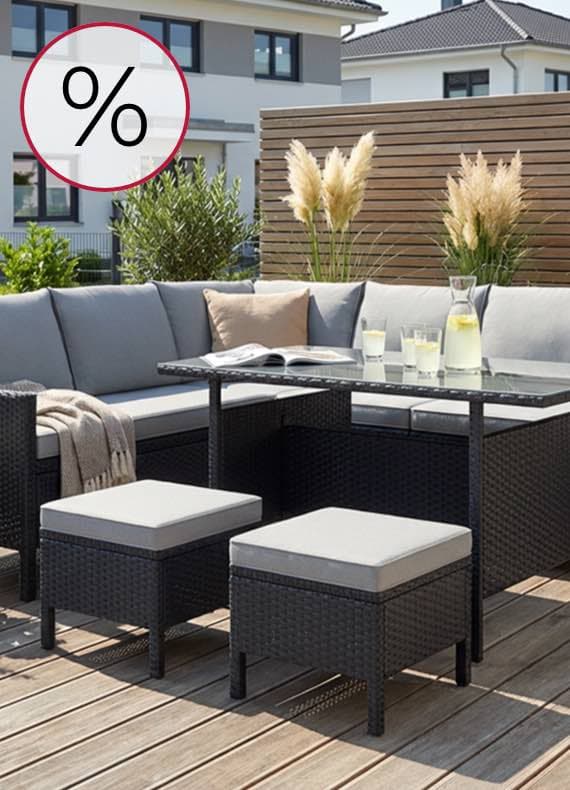 %-Zeichen – Eckige Gartenlounge mit Tisch, Hockern und Getränken auf Holzterrasse vor modernem Haus
