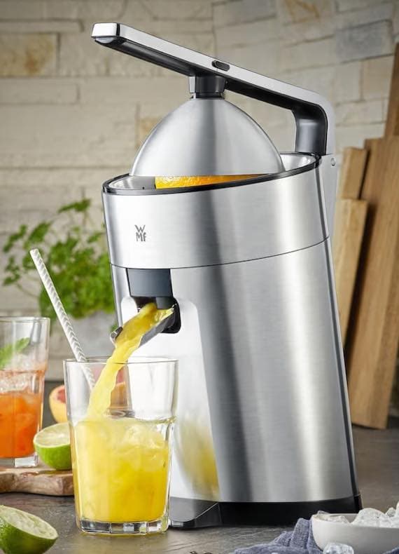 Elektrische Zitruspresse von WMF, die frischen Orangensaft direkt in ein Glas mit Eiswürfeln laufen lässt