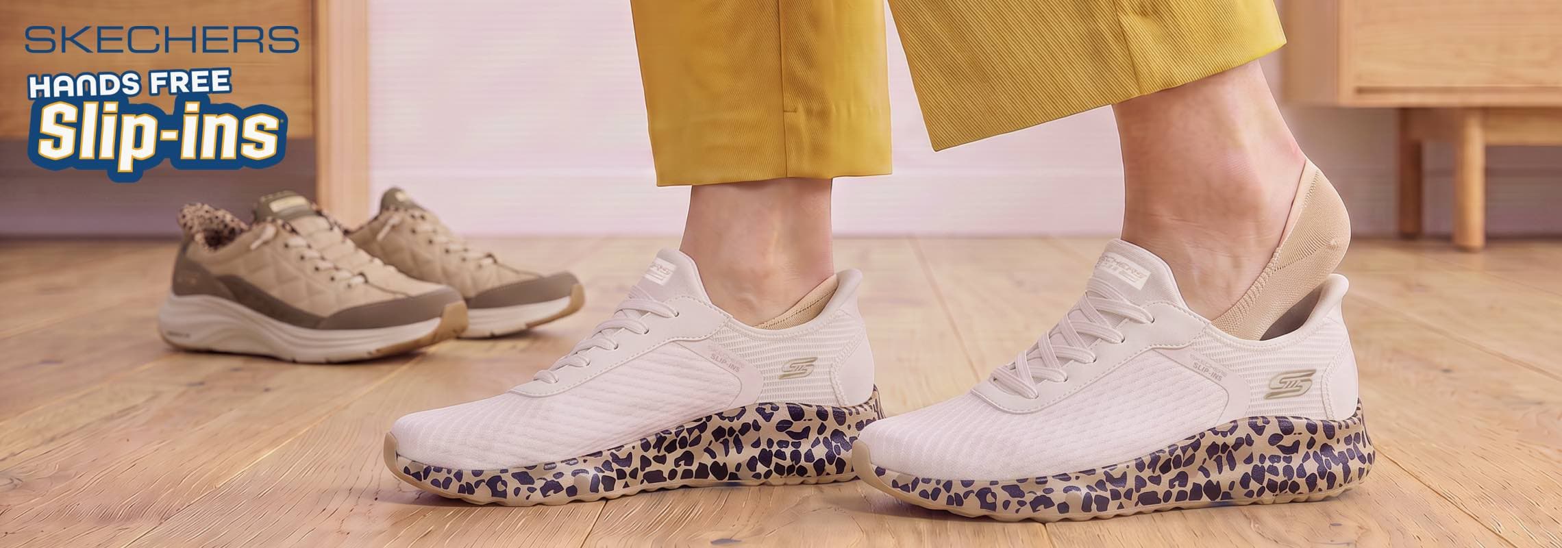 Skechers Hands Free Slip-ins – Person schlüpft freihändig in weiße Sneaker mit gesprenkelter Sohle, weitere Schuhe im Hintergrund
