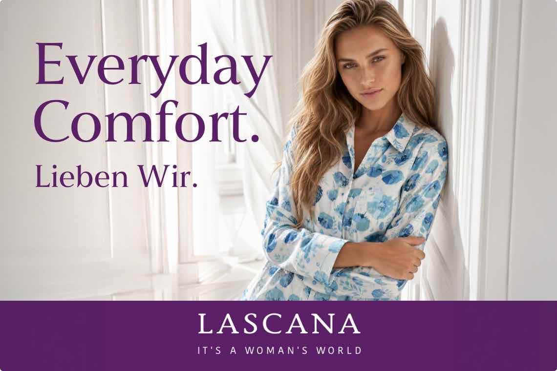 Everyday Comfort. Lieben wir. Frau in gemustertem Schlafanzug lehnt an Wand, LASCANA Logo unten